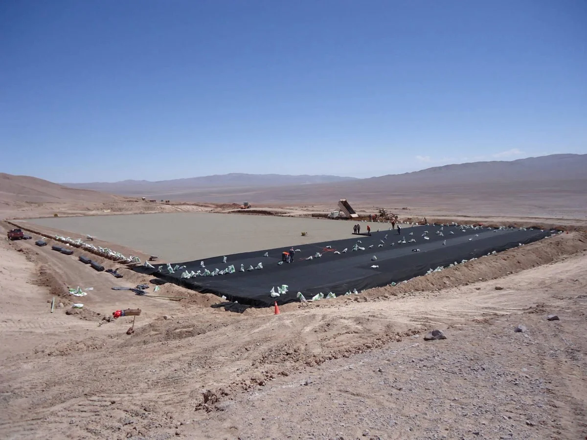 Instalación de geomembrana en el fondo de una piscina en el desierto.